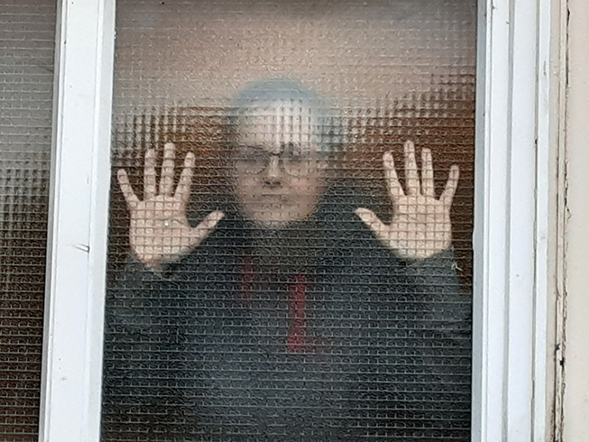 woman standing pressed against textured glass trying to see through it