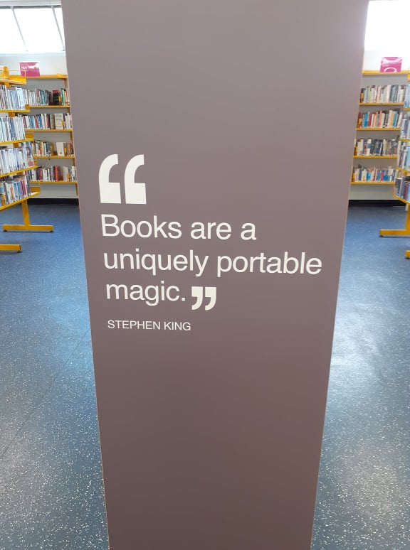 A quote on the side of a shelf, "Books are a uniquely portable magic." - Stephen King.