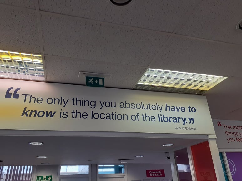 Quote on wall saying, "The only thing you absolutely have to know is the location of the library."