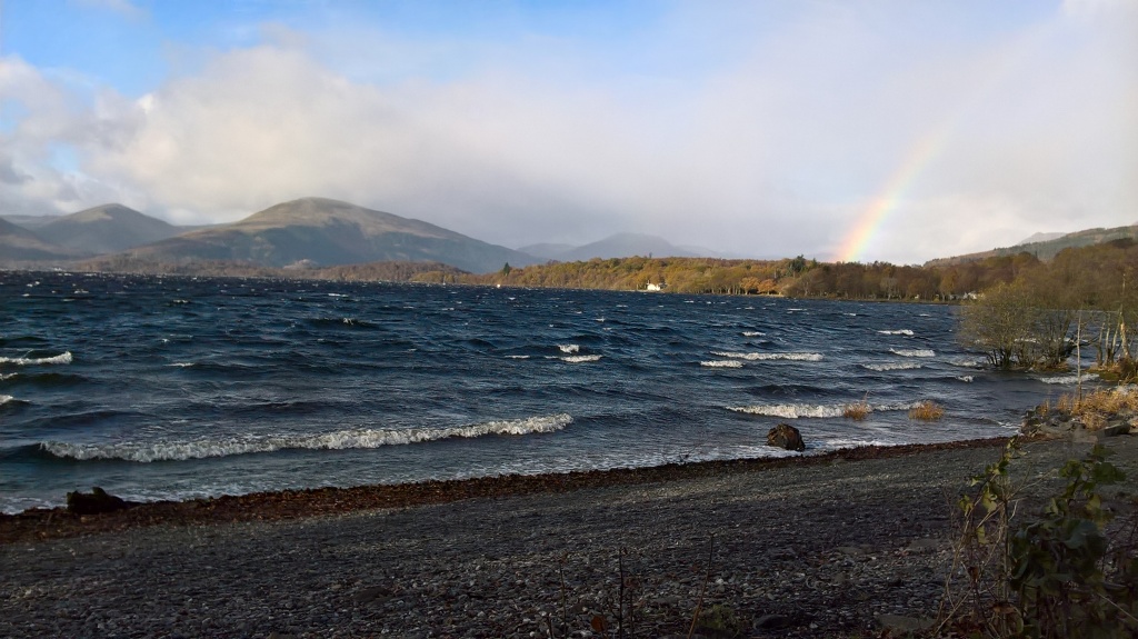 photo of the loch waves rolling into shore with a rainbow in the background