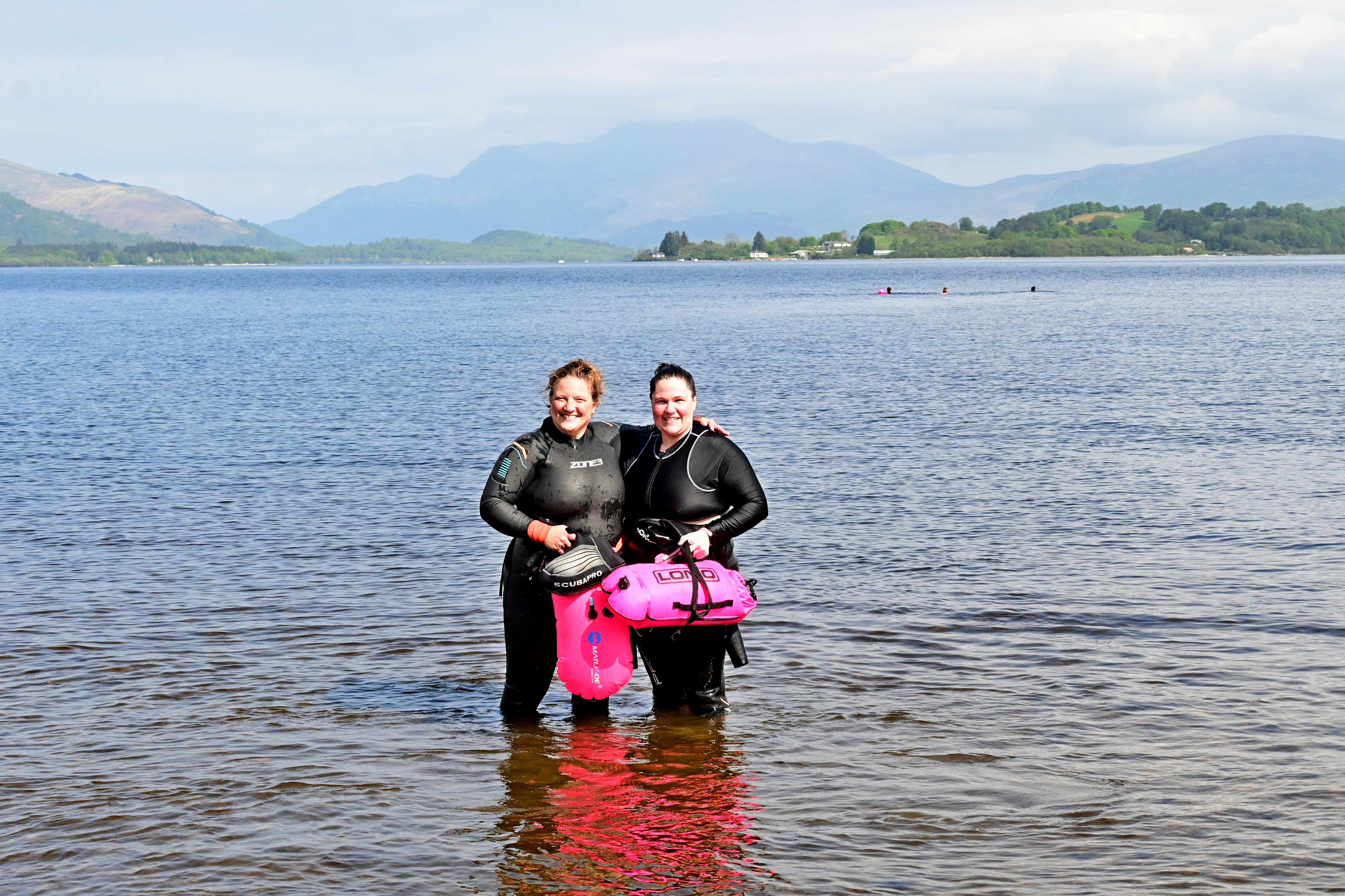 two swimmers staning in the loch up to their knees