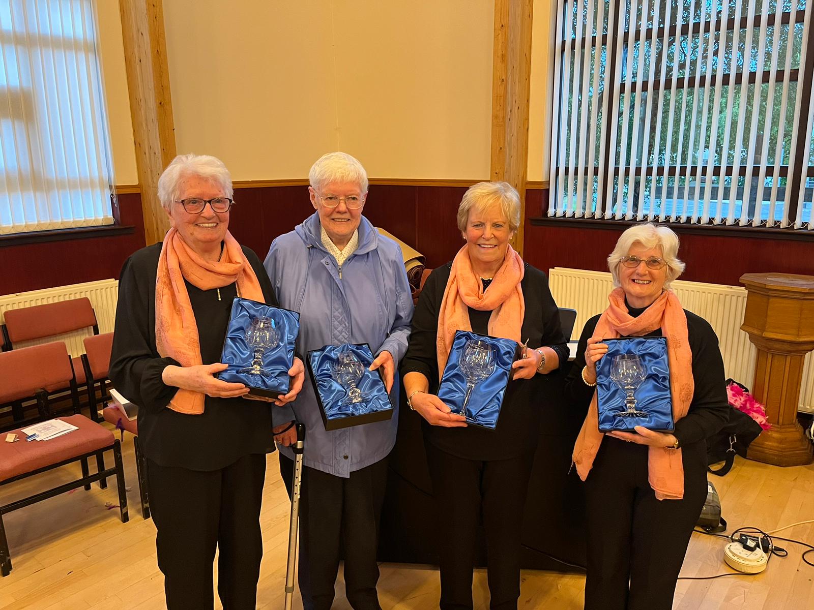 Four women standing holding presentation glasses