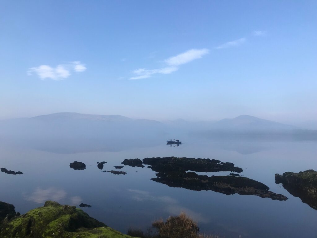 view of a little row boat on the glass flat waters of loch lomond