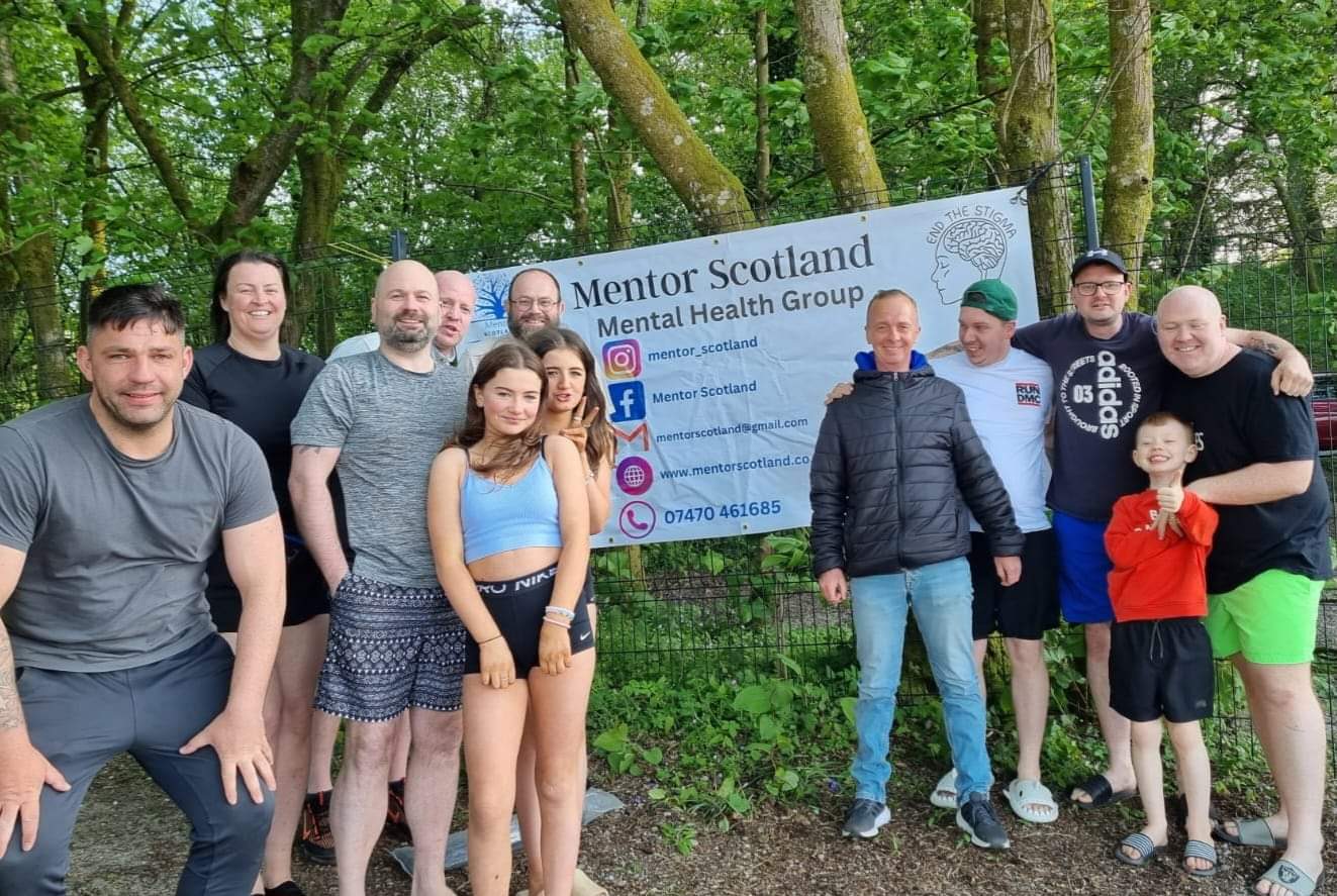 group of people standing in front of Mentor Scotland sign