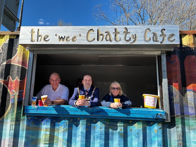 Volunteers leaning through hatch of Wee Chatty Café shipping container