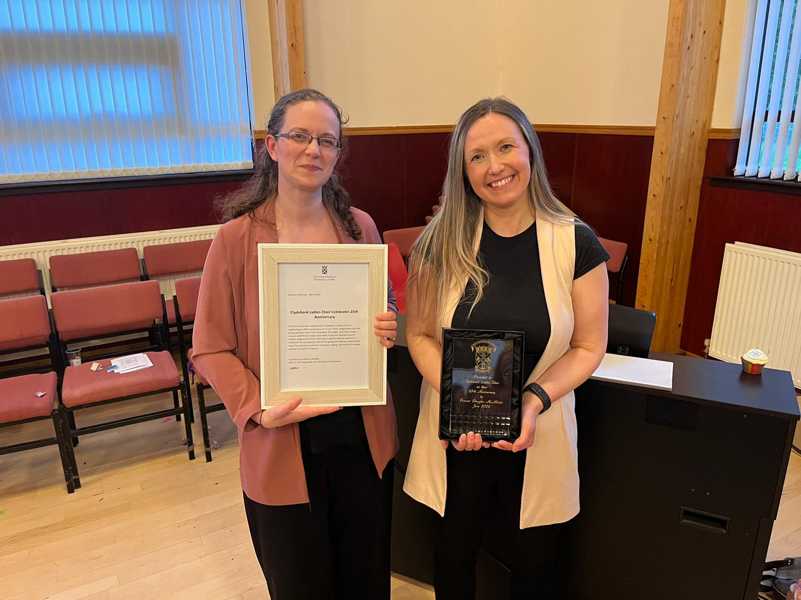 two ladies standing holding a framed statement from Scottish Government