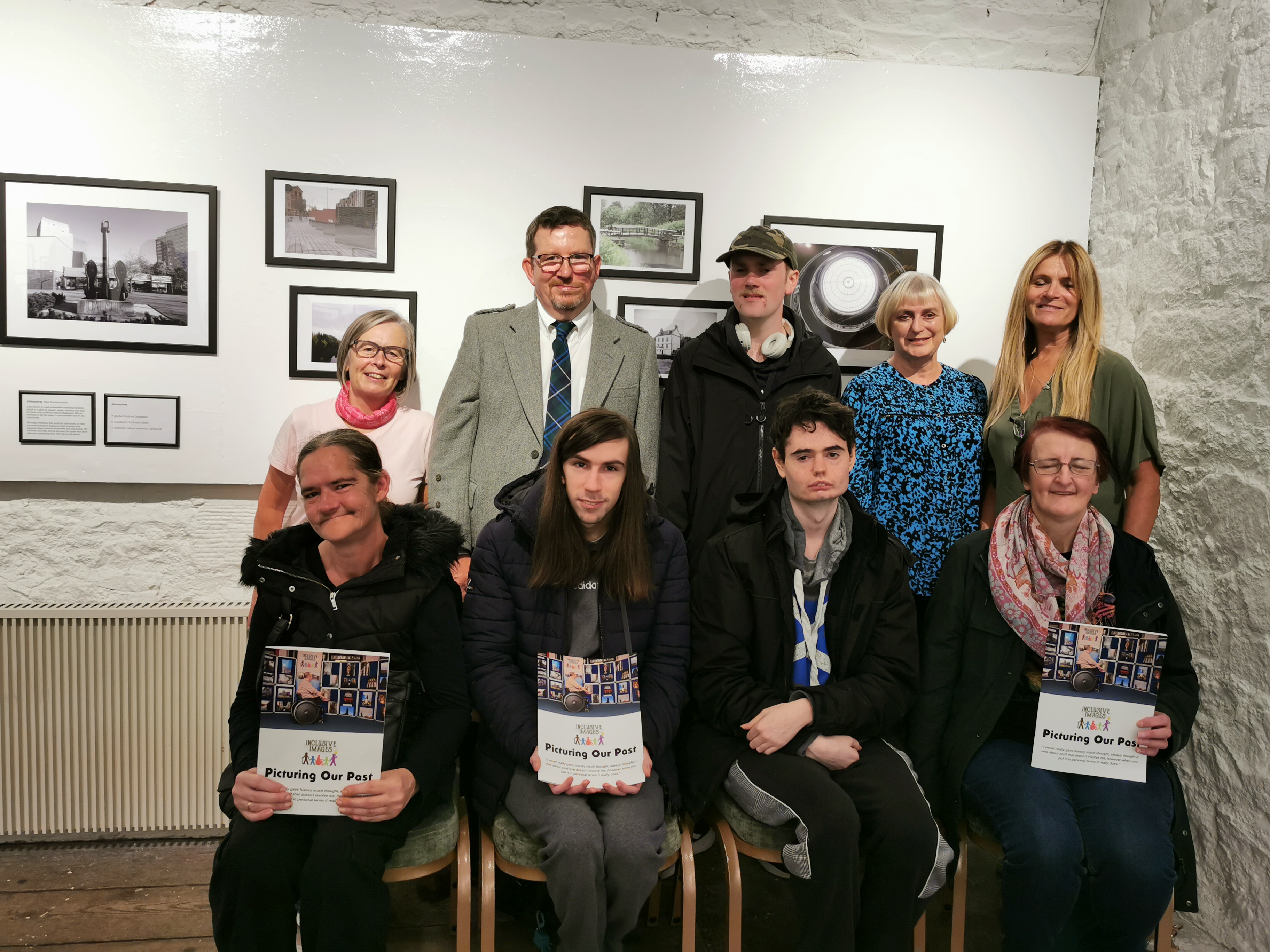 Nine people in a group posing for the camera holding a book