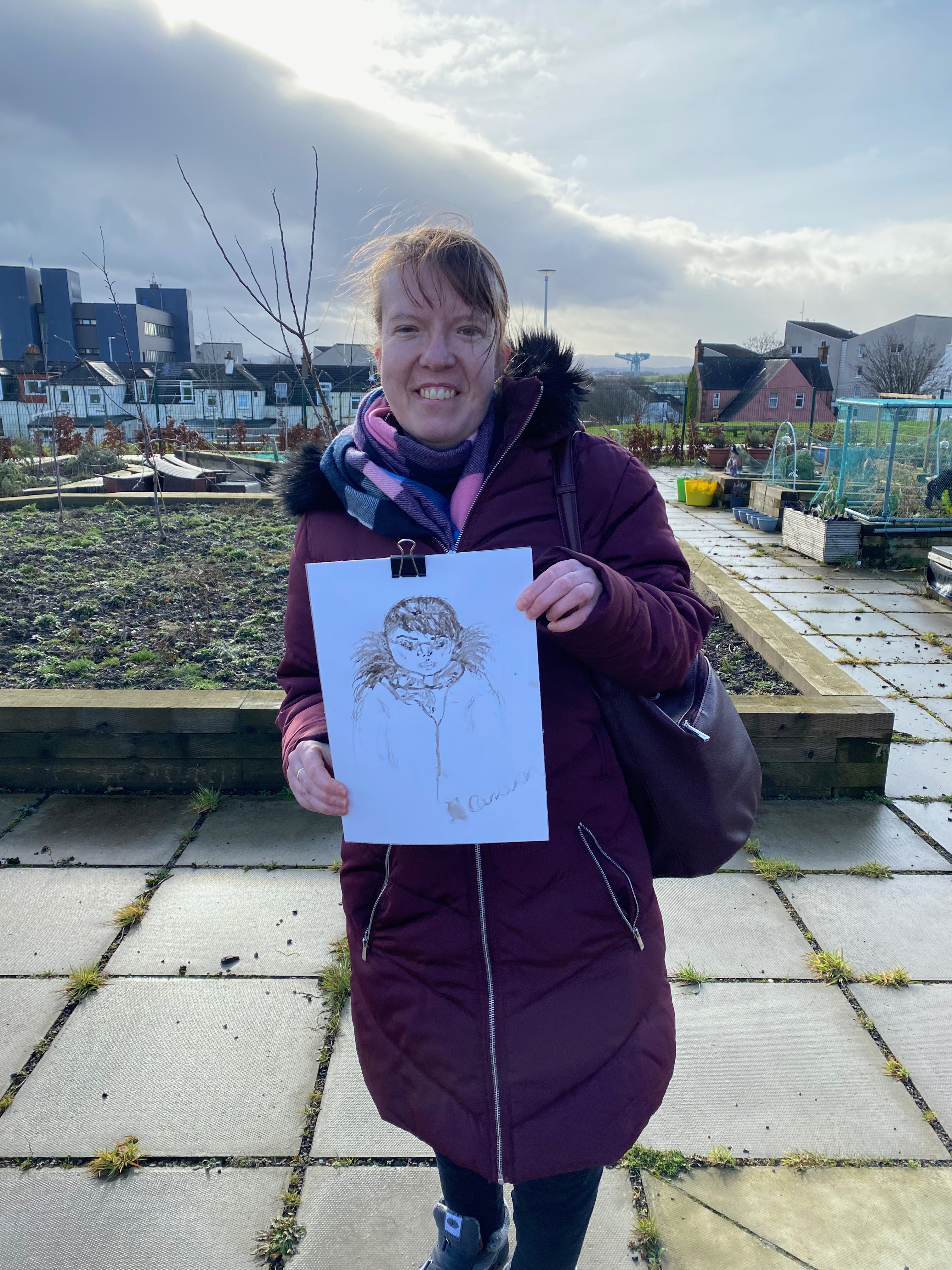 Woman holding portrait made from mud and twigs