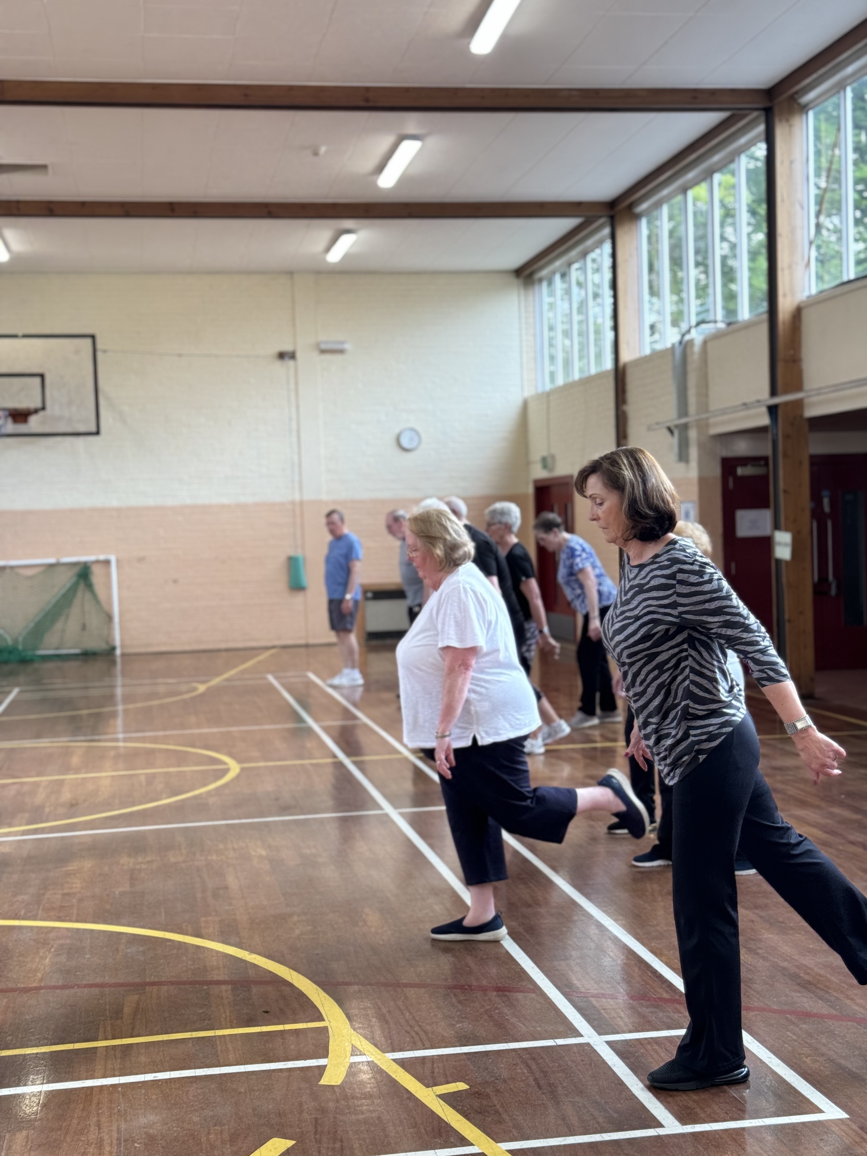 two women taking steps forward in a gym hall