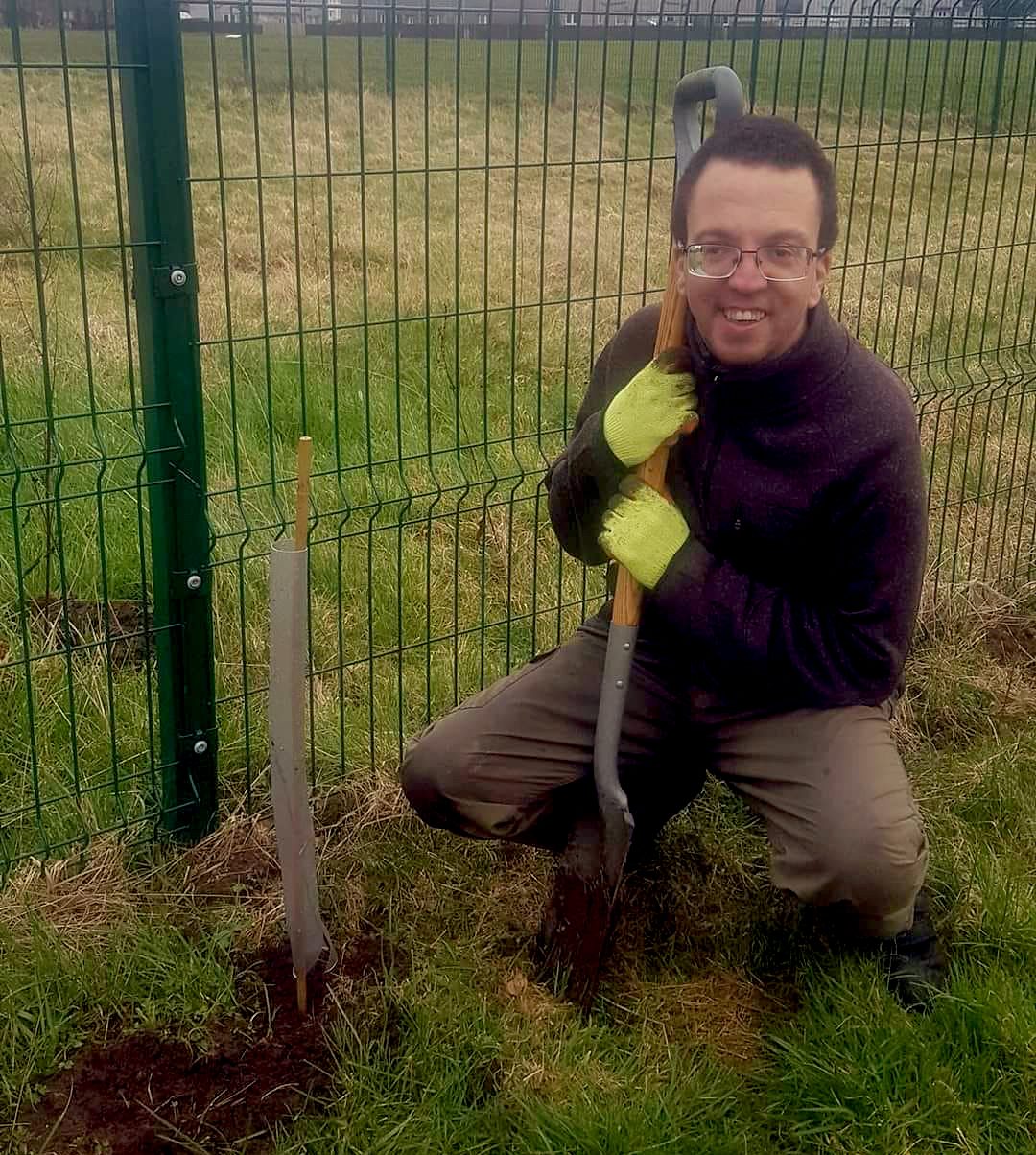 Johnny crouched down digging a hole with a spade