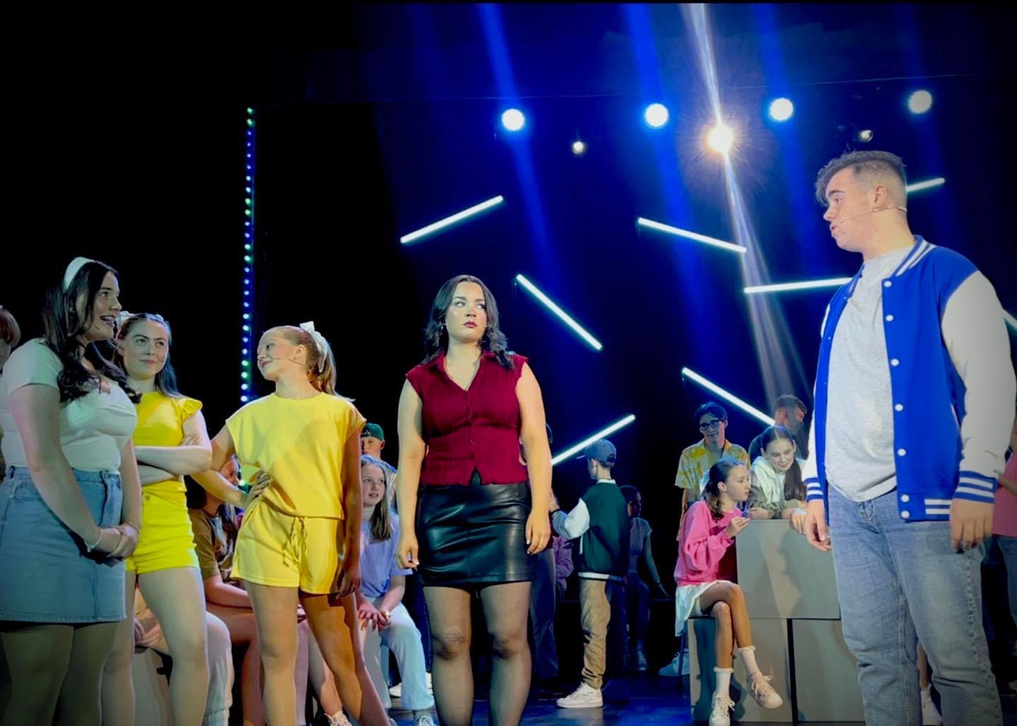 young people standing on a stage mid performance