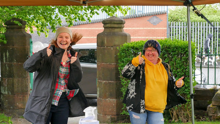 2 women greeting the camera outside, wearing hats and jackets.