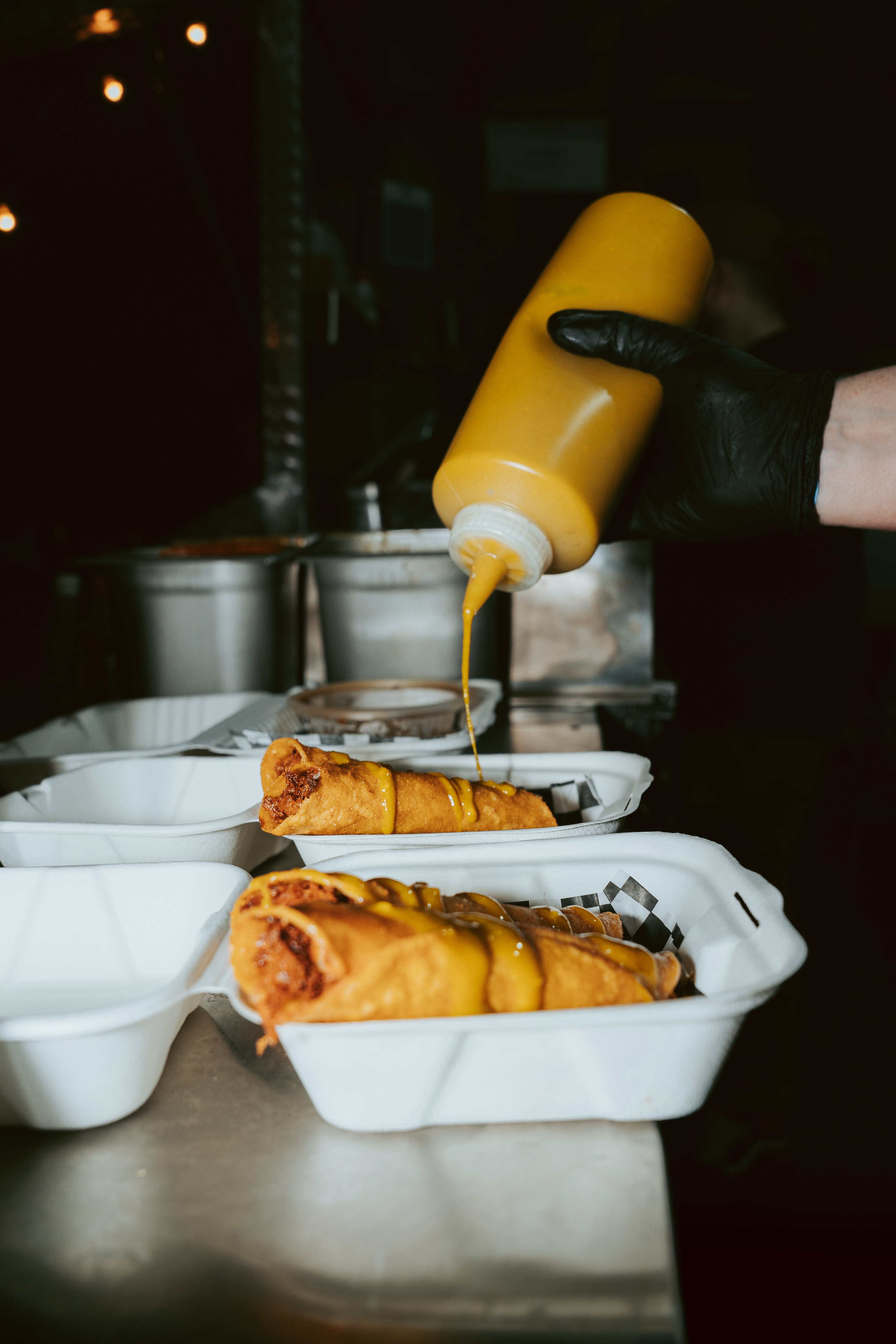 sauce being drizzled over chicken taquitos