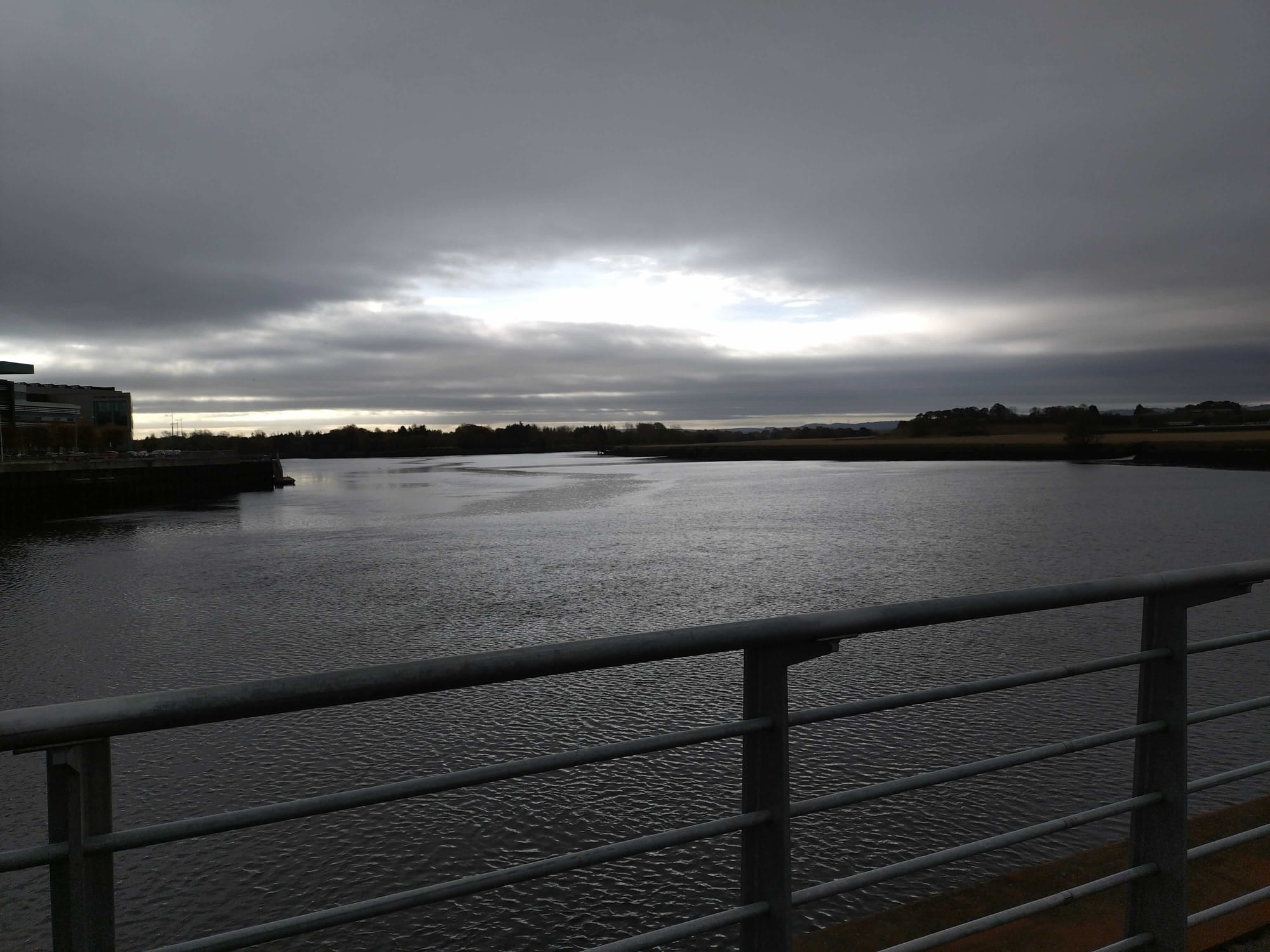 photo of a body of water with sunlight breaking through dark clouds above