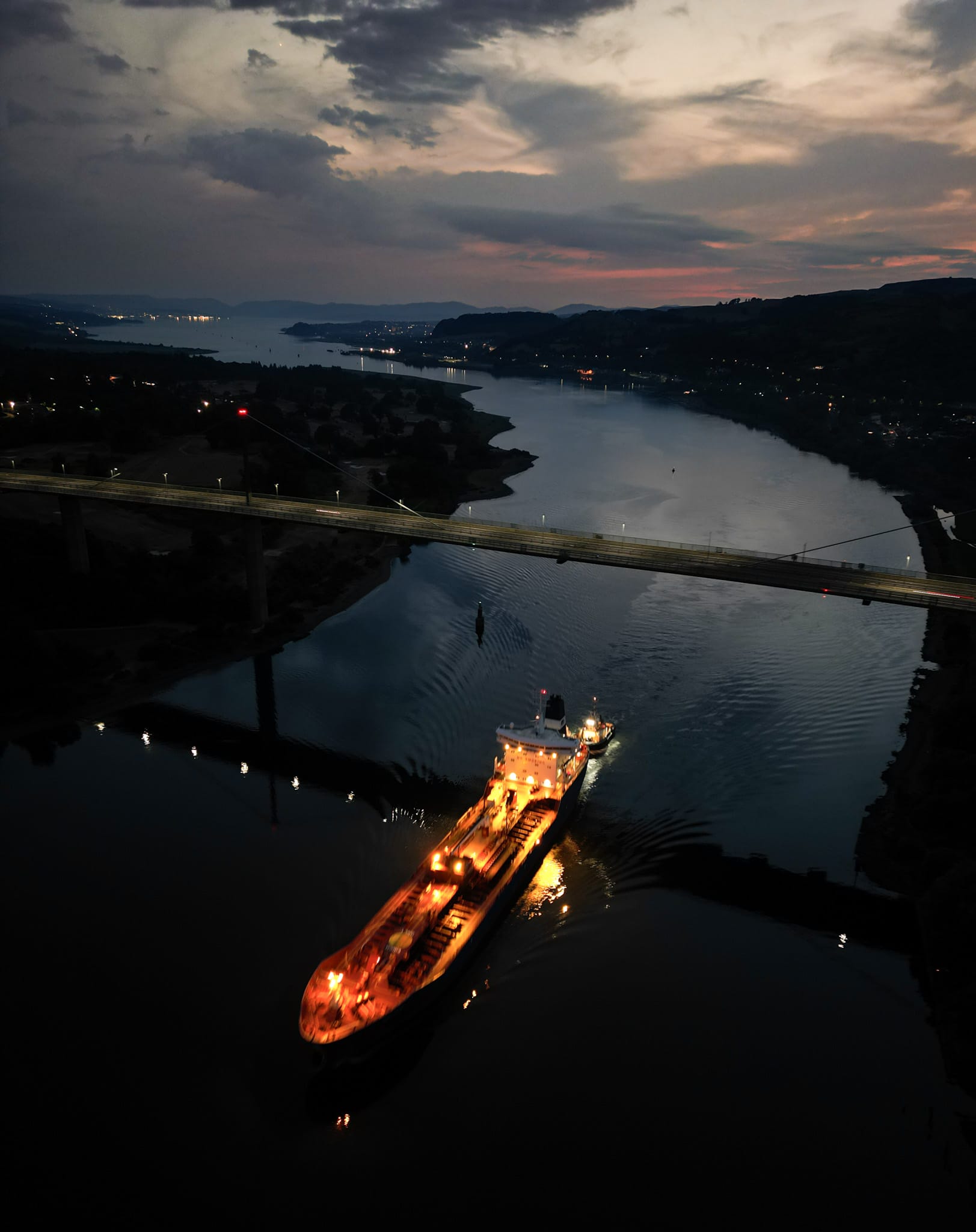Brightly lit tanker sailing under the Erskine Bridge at night time