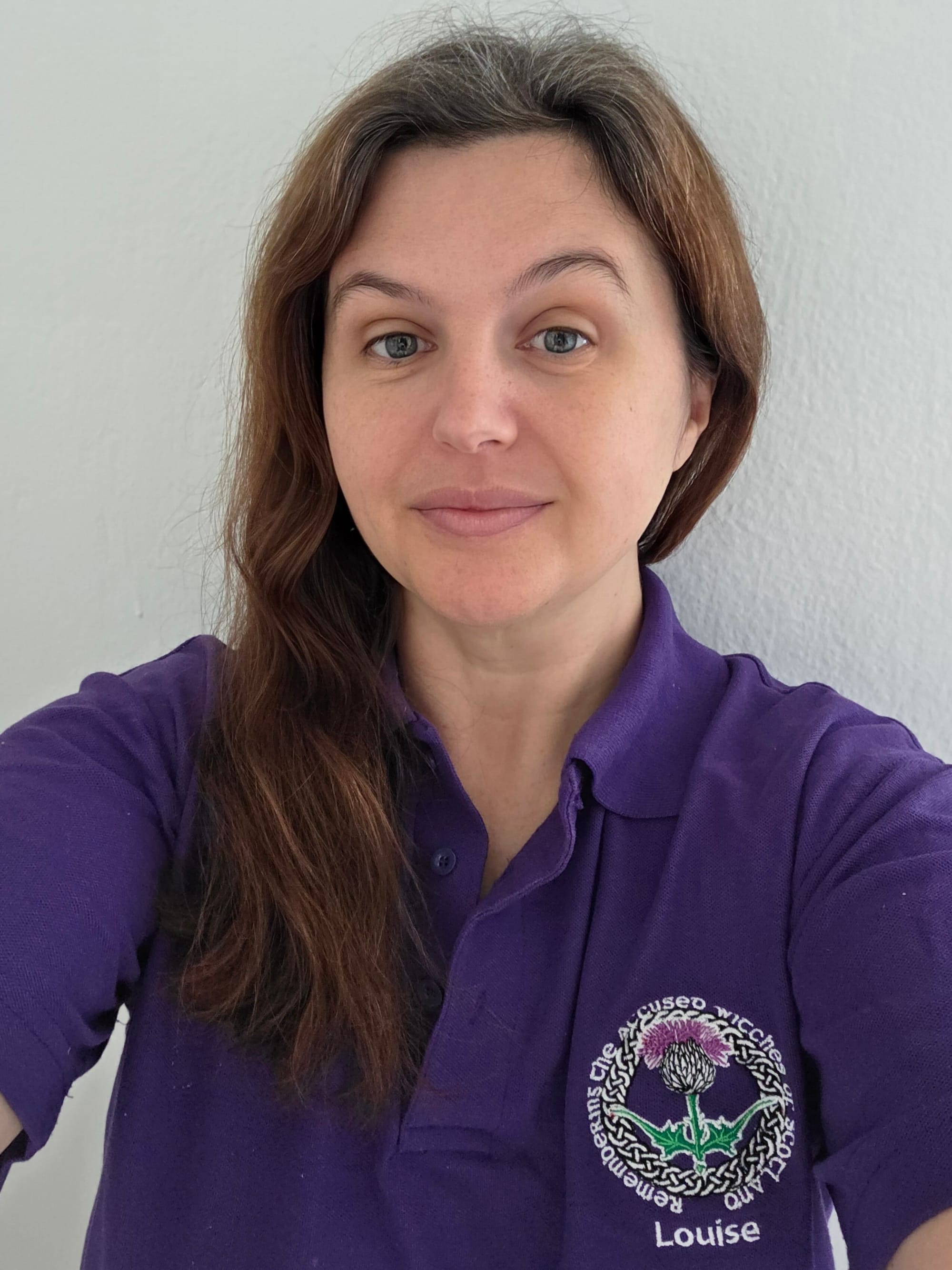 close up selfie of Louise wearing her purple RAWS polo shirt