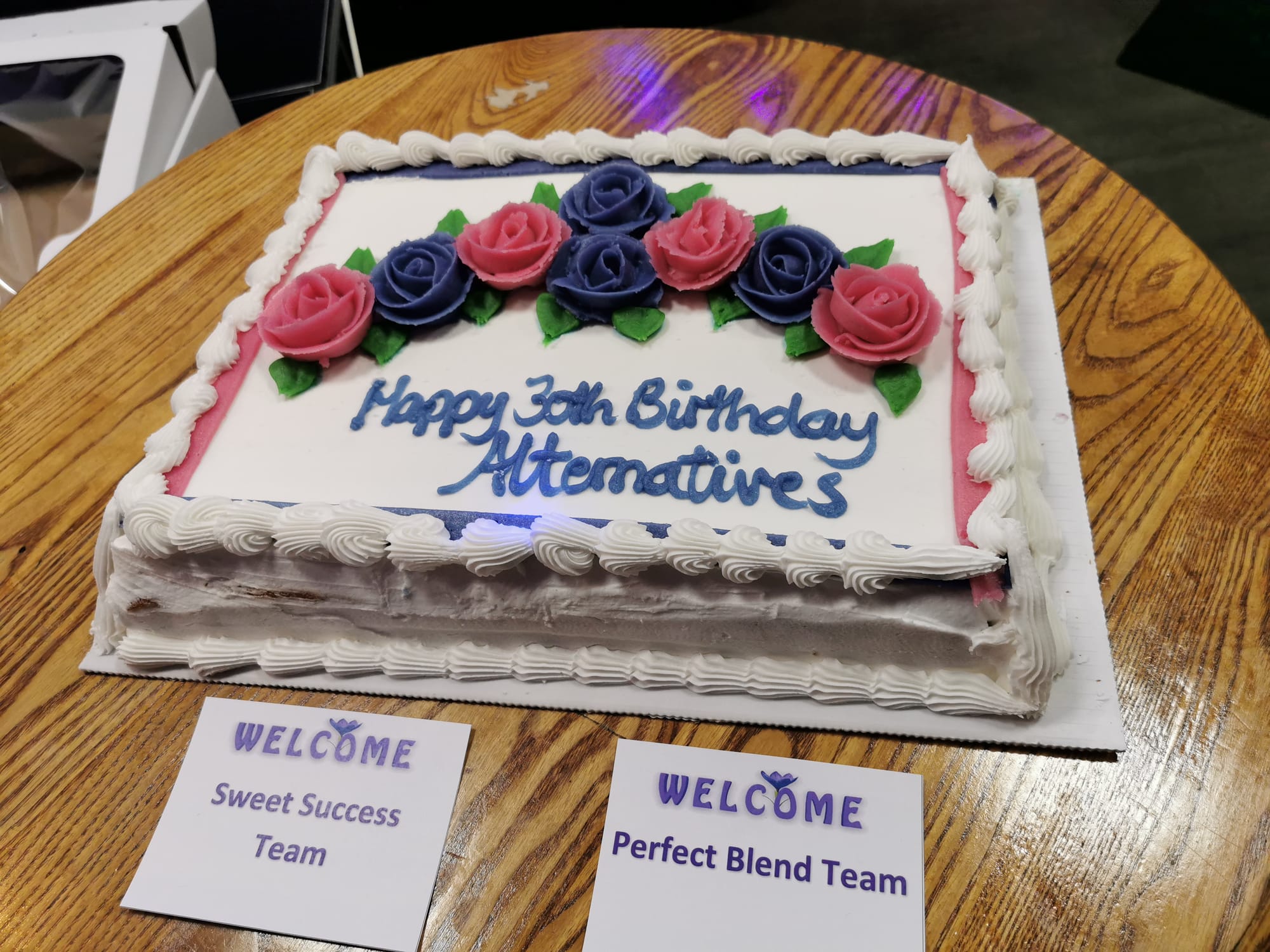 Close up photo of a white, rectangular birthday cake that says "Happy 30th Birthday Alternatives"