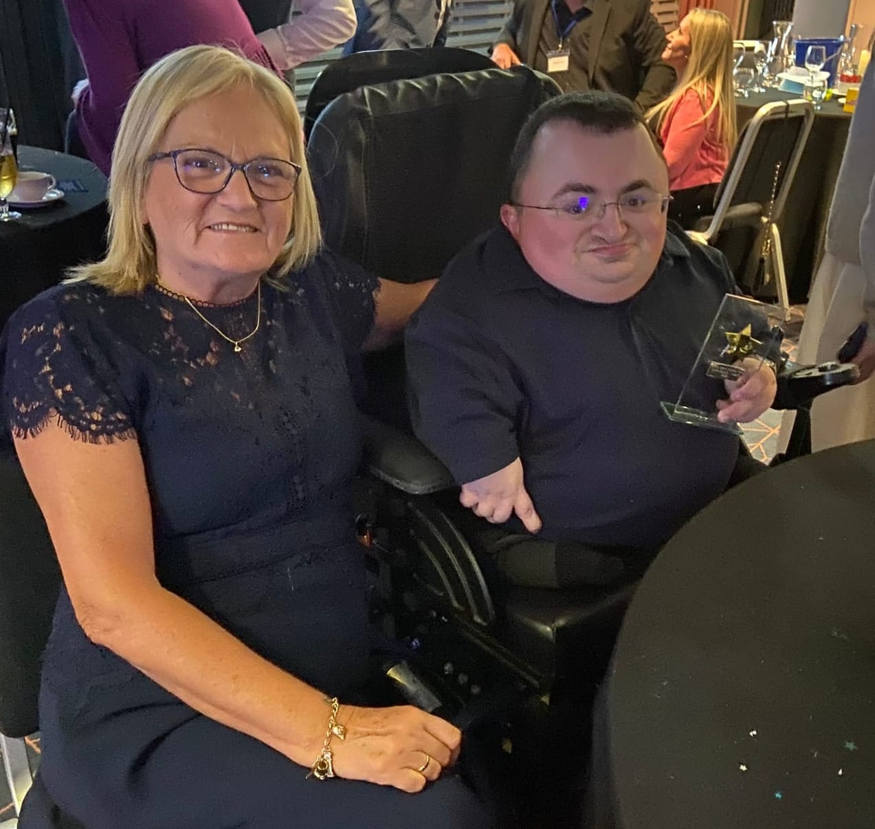Steven holding his award, sitting next to his mother.