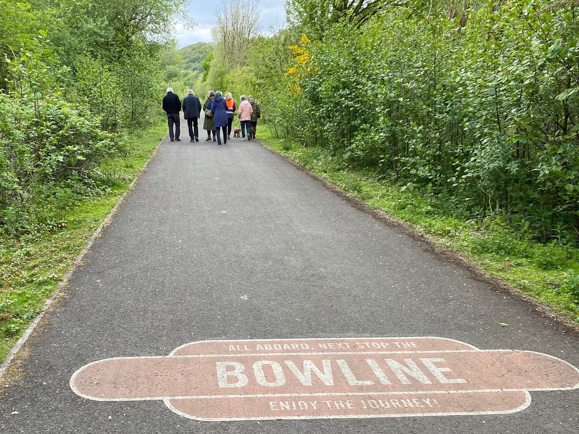 Group of walkers on the canal path in the distance with the signage for the Bowline painted in the forefront
