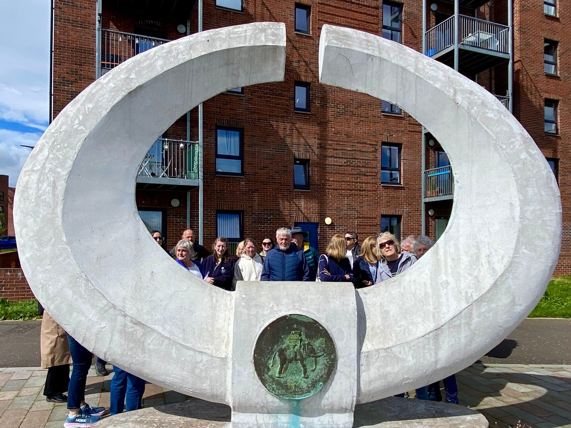 Group of people looking through a white circular sculpture which includes the Dumbarton crest showing an elephant