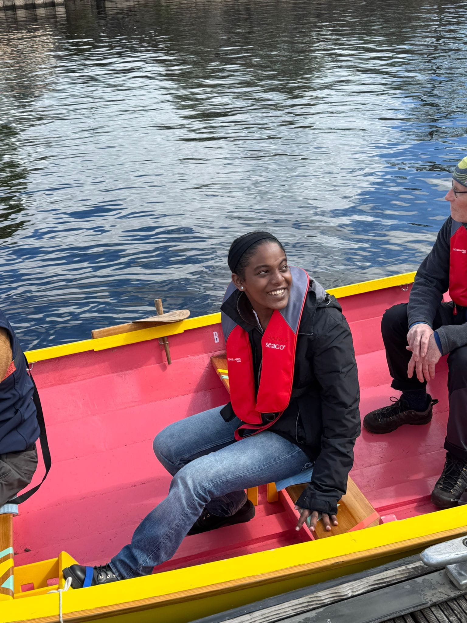 Clydesider volunteer Suhaila sitting in the skiff and smiling up at the photographer