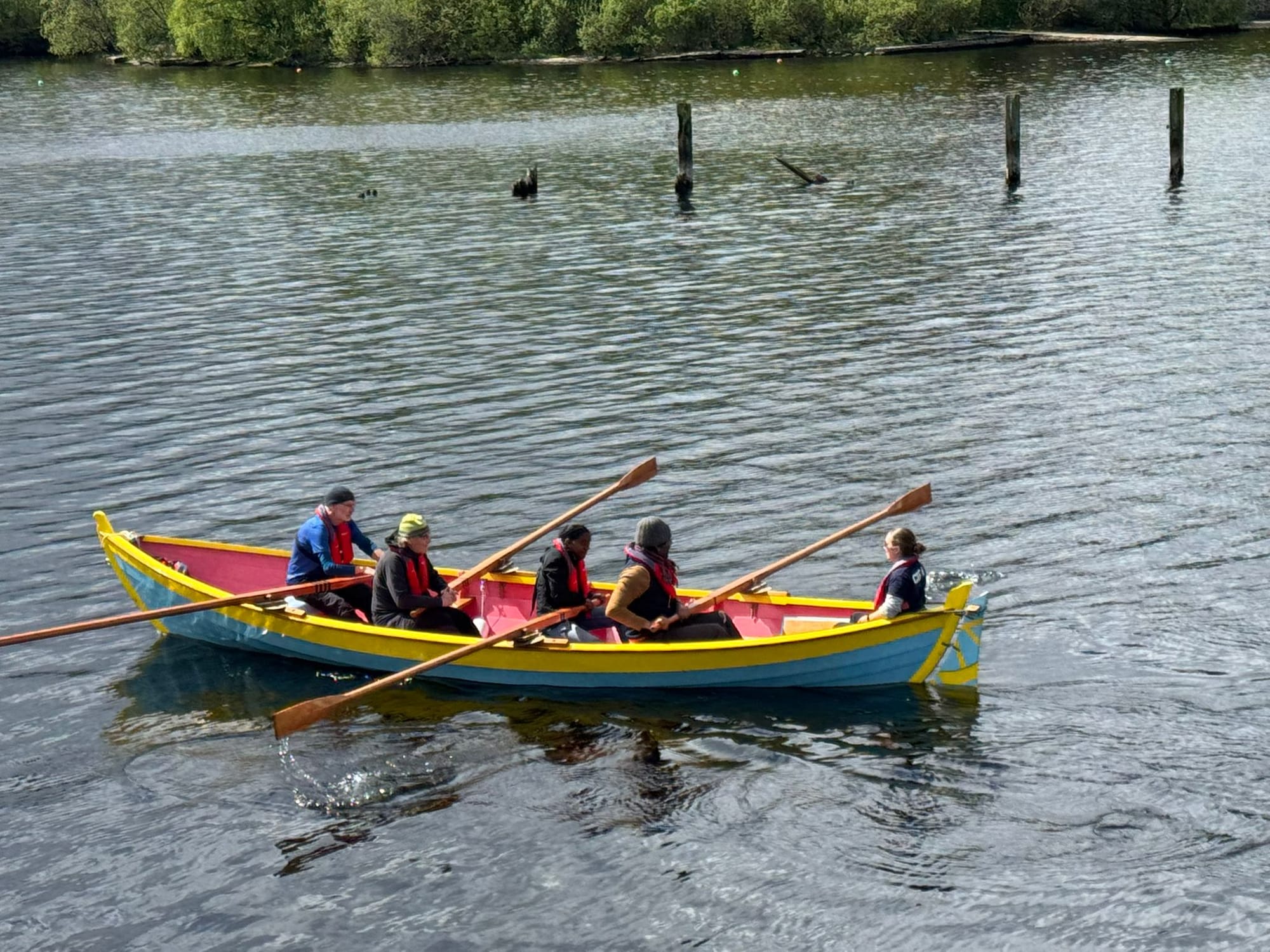 Brightly coloured skiff being rowed on Loch Lomond