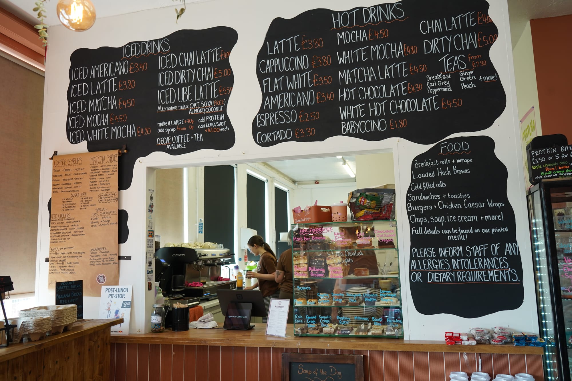 photograph of the serving hatch and cake display with various menu options on the walls round about